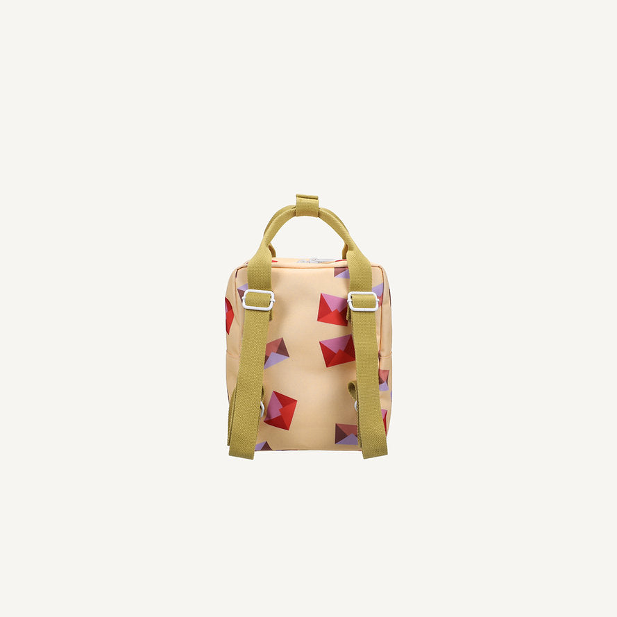 The Sticky Lemon Backpack Small - Special Edition - Snail Mail is a beige kids backpack with green straps and top handle, decorated with red and purple geometric shapes. Made from recycled PET bottles and waterproof lined, shown on a plain white background.