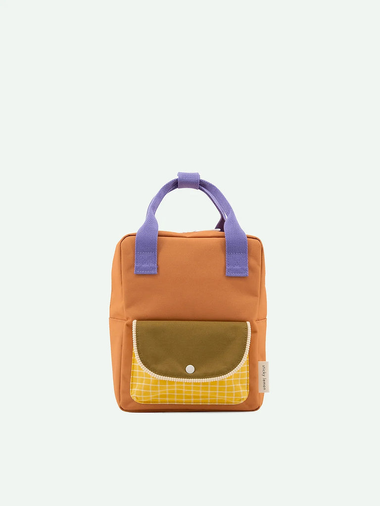 A Sticky Lemon Backpack Small featuring a tan body, violet top handle, and front pockets in yellow plaid and olive green, equipped with a durable YKK zipper, isolated on a white background.
