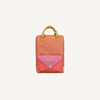 The Sticky Lemon Backpack Large - Envelope - Maple Whirl features a rectangular orange design with yellow handles, a front pocket with a pink flap and red checkered fabric, and adjustable shoulder straps, shown on a plain light background.