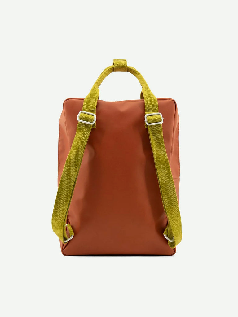 A Lighthouse Red backpack made from waterproof nylon with bright lime green adjustable straps, displayed against a white background. The bag has a sleek, minimalist design, suitable for casual use.