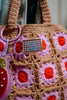 A close-up of the Sticky Lemon Crochet Bag - Lemon Tree - Flower - Campfire Orange, featuring vibrant pink and red flower patterns, a “sticky lemon” label, and a ladybug-shaped keychain attached to the handle—perfect as a charming kids bag.