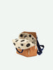 A stylish, open Sticky Lemon Backpack Small in Treehouse Brown and white polka dots with a tan bottom and a navy blue strap, crafted from waterproof nylon against a plain light background.