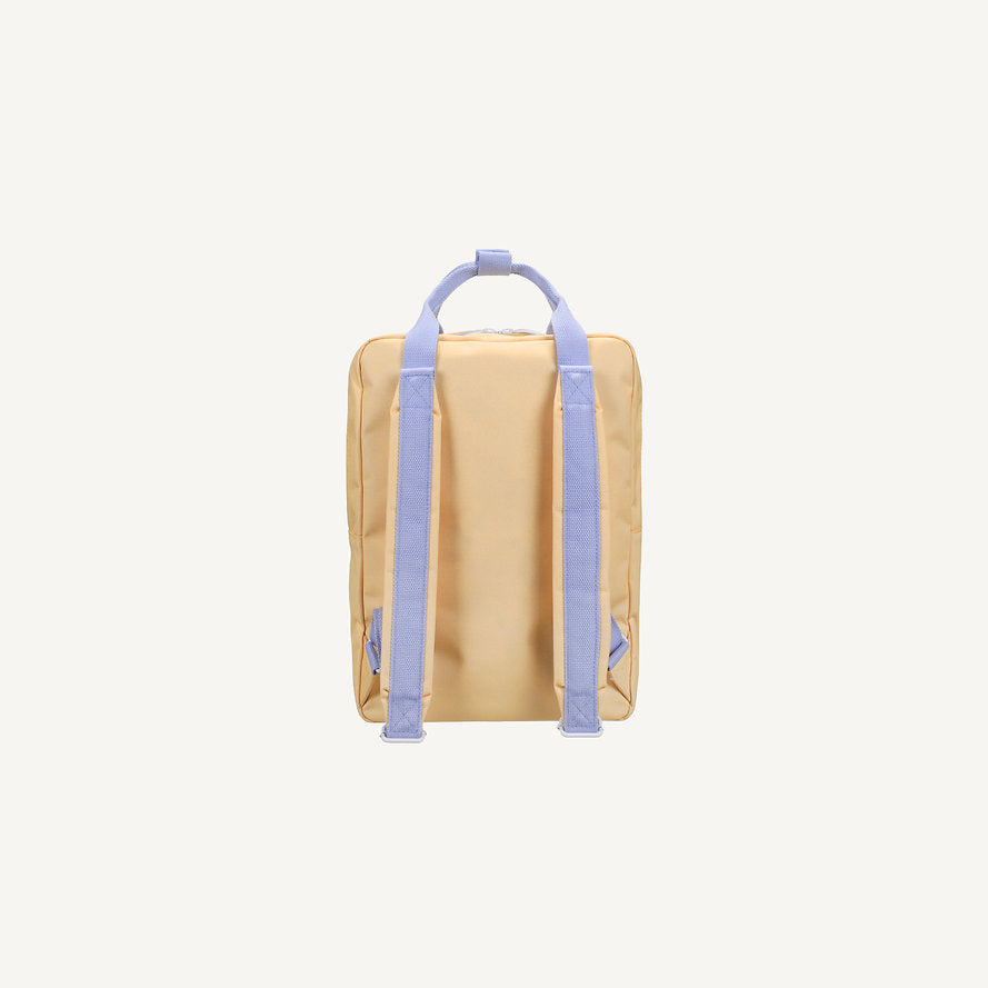 The Sticky Lemon Backpack Large - Envelope - Twiggy Beige is a beige rectangular kids backpack made from recycled PET bottles, with light purple adjustable shoulder straps and a matching top handle, shown against a plain white background.