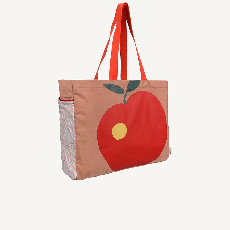 The Sticky Lemon Shopper - Apple is a colourblock tote with red handles, a bright red apple graphic with yellow spot and green leaves on light brown, plus playful red and white plaid sides for a bold, eye-catching look.