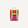 The Sticky Lemon Backpack Large | Color Blocking | Gravel Orange + Rosette Pink is a small, colorful backpack made from recycled PET bottles. It features a vibrant orange top half and a bright pink bottom half, with adjustable shoulder handles, contrasting pale green straps and accents, including a front buckle. The backpack is set against a plain white background.