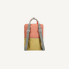 The Sticky Lemon Backpack Large | Color Blocking | Coral Pink + Reed Green features a coral pink top, reed green bottom, gray adjustable straps, and top handle. Made from recycled PET with a waterproof lining, shown on a plain light background.
