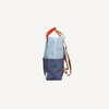 Side view of the Sticky Lemon Backpack Large | Color Blocking | Bissou Blue + Blue Whale, made from recycled PET bottles with a light blue top, dark blue bottom, tan straps, red handle, and front pocket against a white background.
