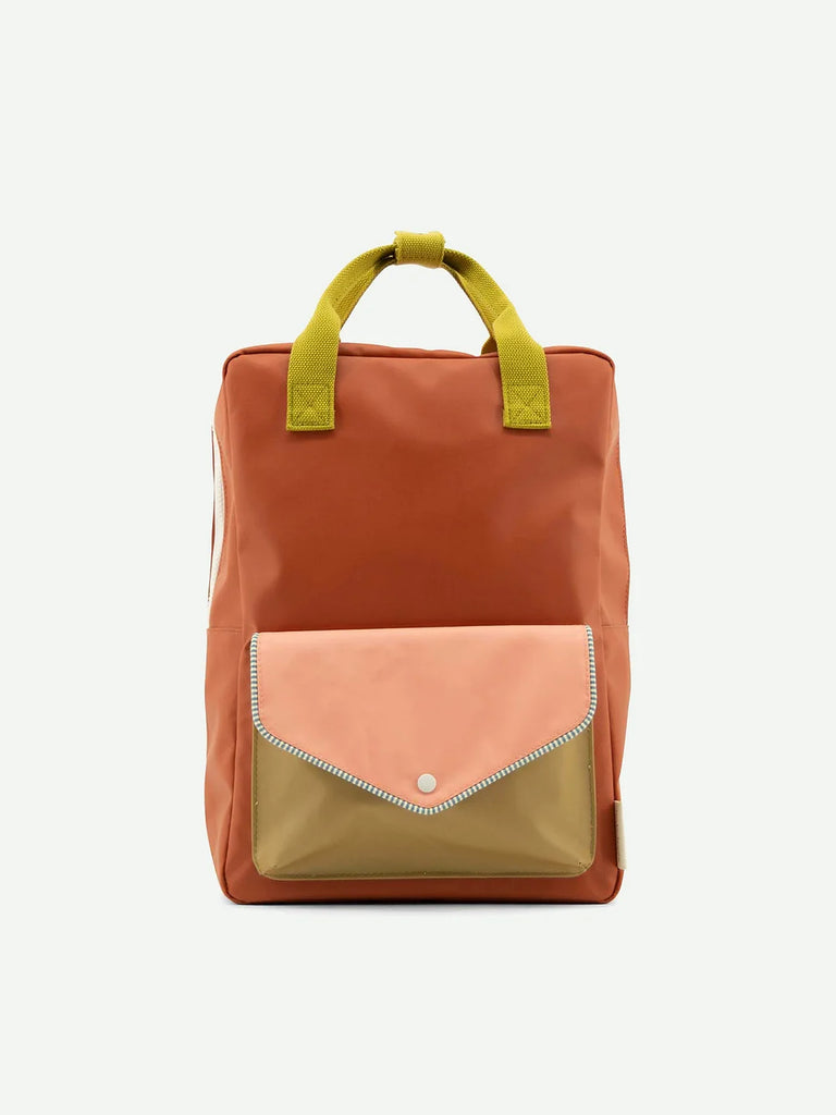 A stylish Sticky Lemon Backpack Large from the Envelope Collection in Lighthouse Red, made from waterproof nylon with a terracotta and peach color scheme and lime green shoulder handles, featuring a front flap with a snap button closure and a white stitched detail.