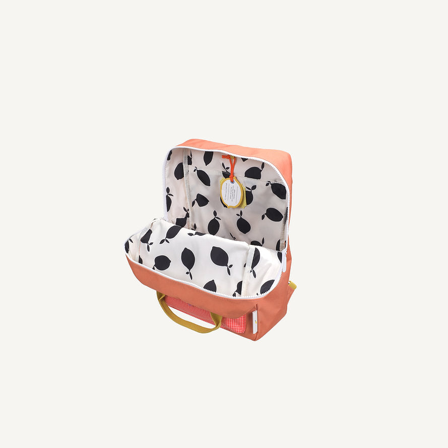 The Sticky Lemon Backpack Large - Envelope - Maple Whirl features pink fabric, yellow handles, a white interior with a black leaf pattern, a yellow circular label inside, and adjustable shoulder straps for comfort.