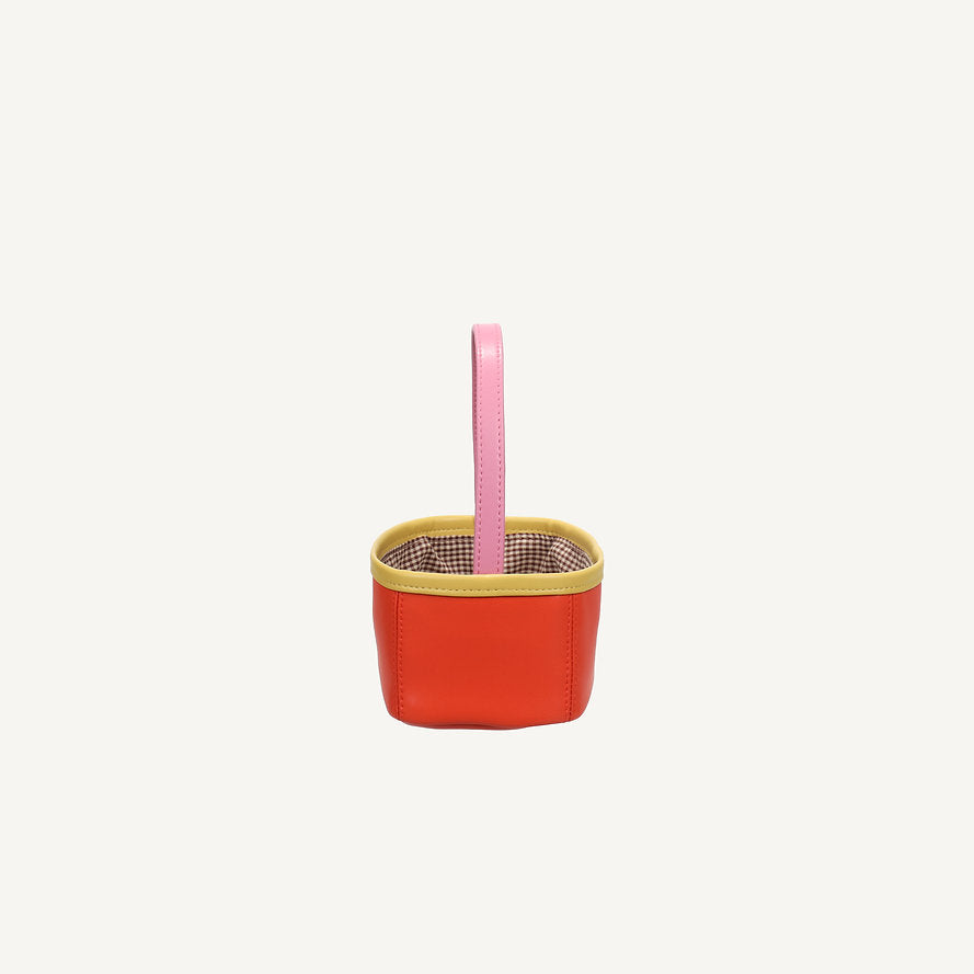The Sticky Lemon Treasure Bag - Campfire Orange is a small, square PU leather bag with yellow trim, a pink handle, and a brown checkered interior, displayed on a plain white background.