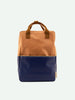 A Sticky Lemon Backpack Large in the Morning Sky color blocking, with a navy blue bottom and a light brown top, featuring a sturdy brown handle and a YKK zipper, isolated on a white background.