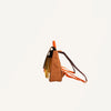 Side view of the Sticky Lemon School Bag | Better Together | Leather Ball, a brown and black backpack with orange straps, crafted from waterproof nylon and recycled bottles. It features a partially open zippered main compartment with a folder partially peeking out against a plain white background.