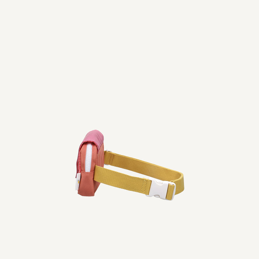 The Sticky Lemon Fanny Pack Small - Envelope - Rosebay Pink is a compact, rectangular recycled PET bag in pink and red hues, featuring a zip closure and yellow adjustable strap with a white buckle, shown on an off-white background.