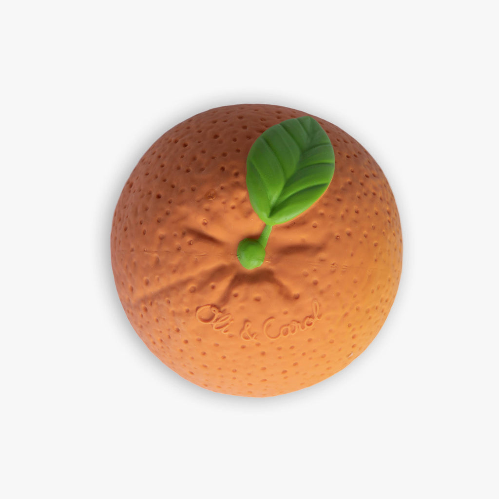 The Orange Baby Ball is a round, orange sensory toy made from natural rubber with a green leaf on top and a textured dotted surface that mimics orange peel, photographed against a white background.