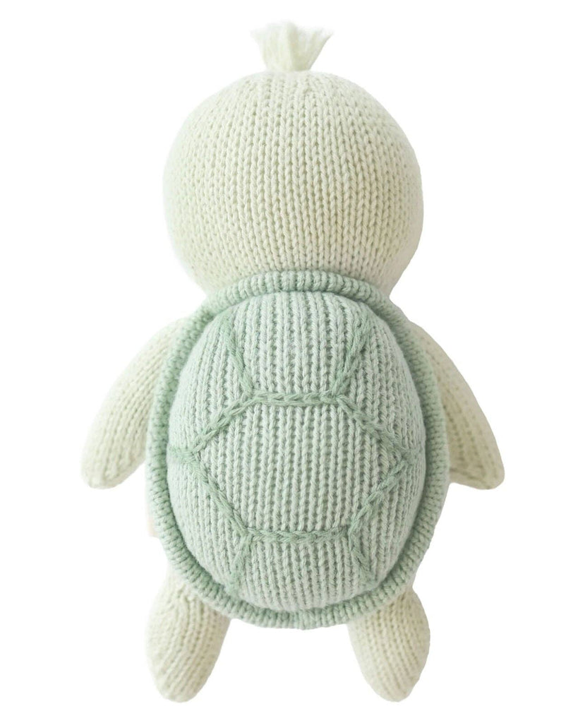 The Cuddle + Kind Baby Sea Turtle (Kelp Green) is a hand-knit plush toy made from natural Peruvian cotton yarn, featuring a light green color and textured shell with a simple, soft design and no visible facial features when viewed from above.