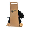 Pull-Along Walter is a black stuffed dog with wooden wheels, designed as an adorable pull-along toy. Partially hidden by a brown paper bag labeled "Walter," only its head and legs peek out.
