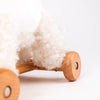 Close-up of Pull-Along Lola, a wooden toy with light brown wheels and soft, wool-like white curls, shown against a plain white background—ideal for developmental play or as a thoughtful toddler gift.