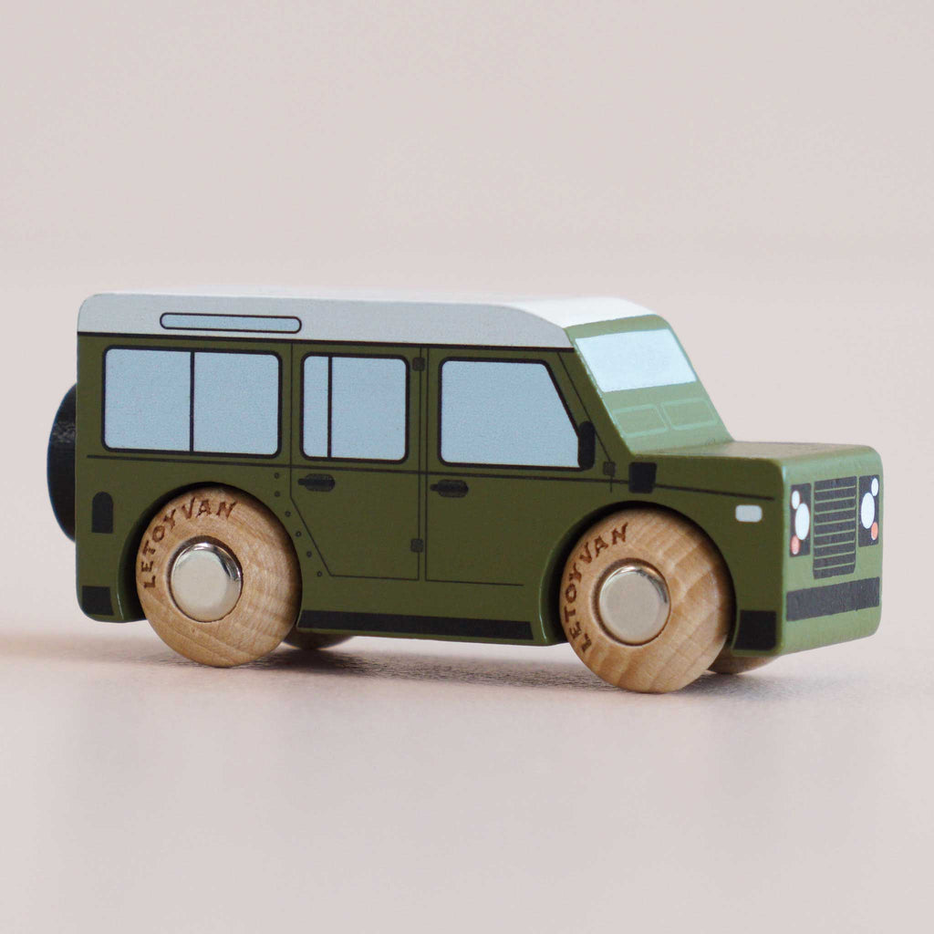 The No. 27 GT150 Archie, made in England, features a boxy green wooden body with black windows and light wooden wheels—perfect for inspiring imaginative play as it sits on a light surface.