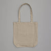 The Cats Tote Bag, a plain beige canvas tote with two long handles, is displayed on a light gray background. Its unadorned design highlights the natural fabric texture, complemented by an inside pocket for added practicality.