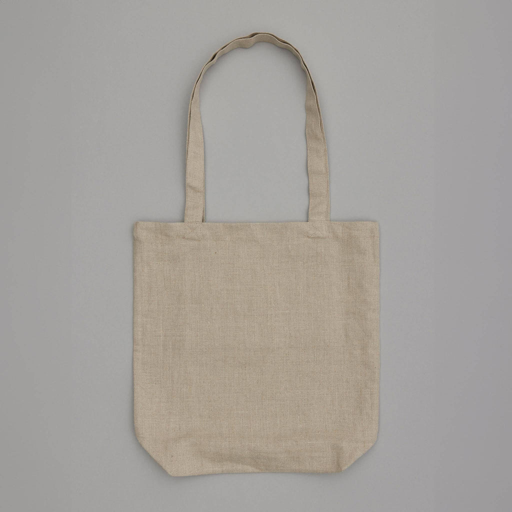 The Cats Tote Bag, a plain beige canvas tote with two long handles, is displayed on a light gray background. Its unadorned design highlights the natural fabric texture, complemented by an inside pocket for added practicality.