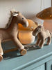 Two brown plush toy horses, one of which is Pull-Along Henry—a delightful wooden horse toy on wheels with a pull string—stand on a blue-green surface. A mushroom-shaped lamp from Egmont Toys glows softly in the background, adding a gentle warmth to the scene.