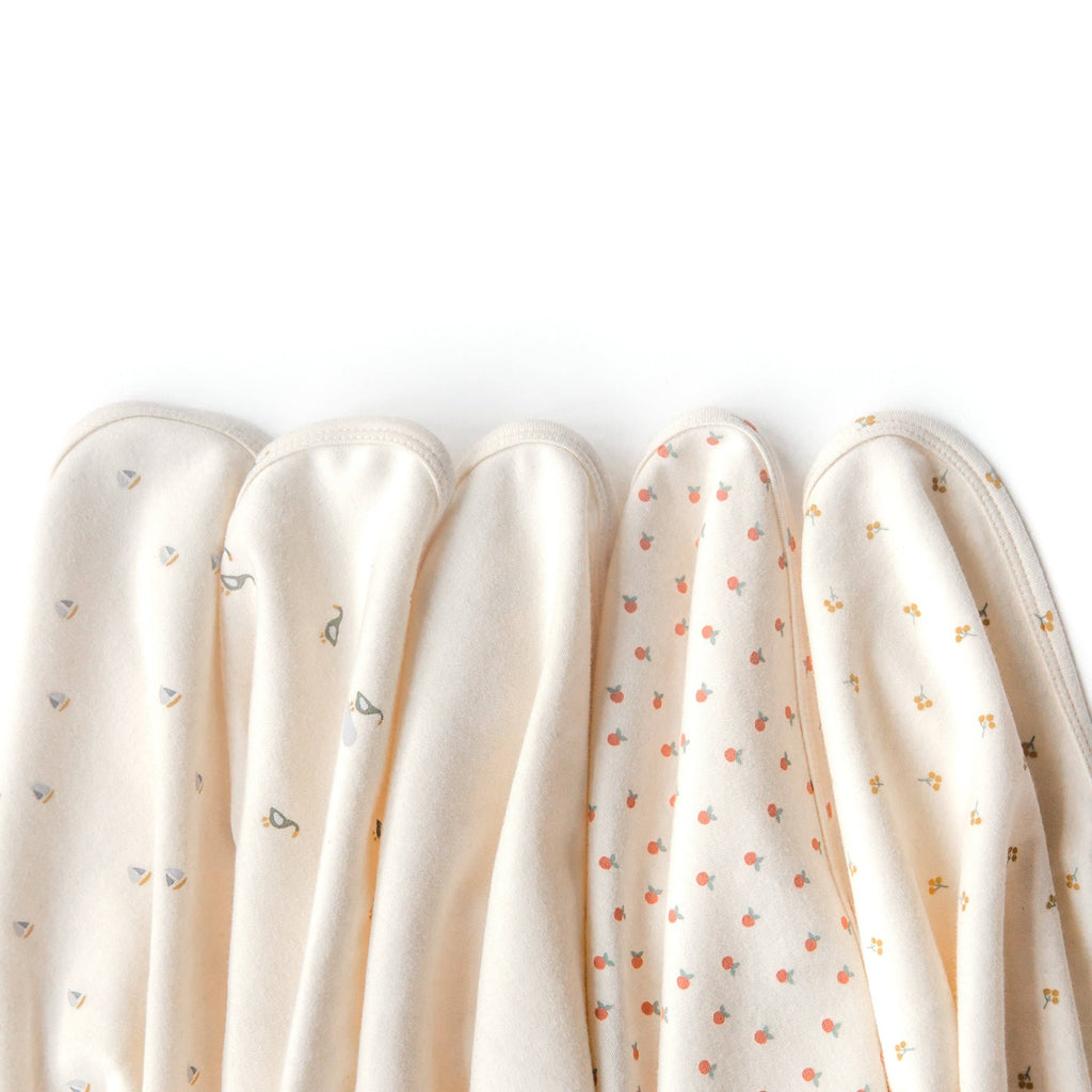 Five soft, cream-colored Organic Baby Blanket – Gold Sprig blankets made from GOTS-certified organic cotton display subtle gold sprig patterns and are neatly arranged side by side on a white background.