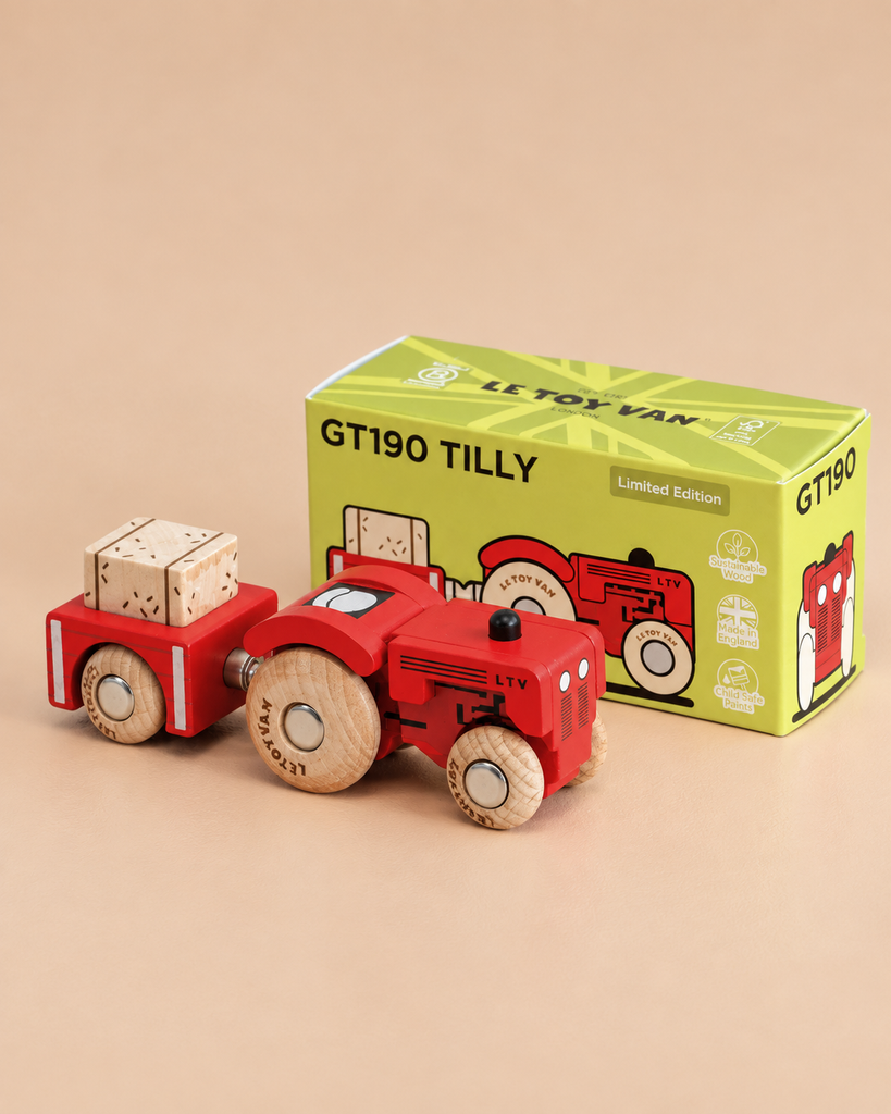 A charming vintage wooden tractor, painted red and featuring a trailer with wooden crates, sits in front of the No. 34 GT190 Tilly | Made in England green toy box on a beige background—perfect for inspiring imaginative play in any countryside toy collection.