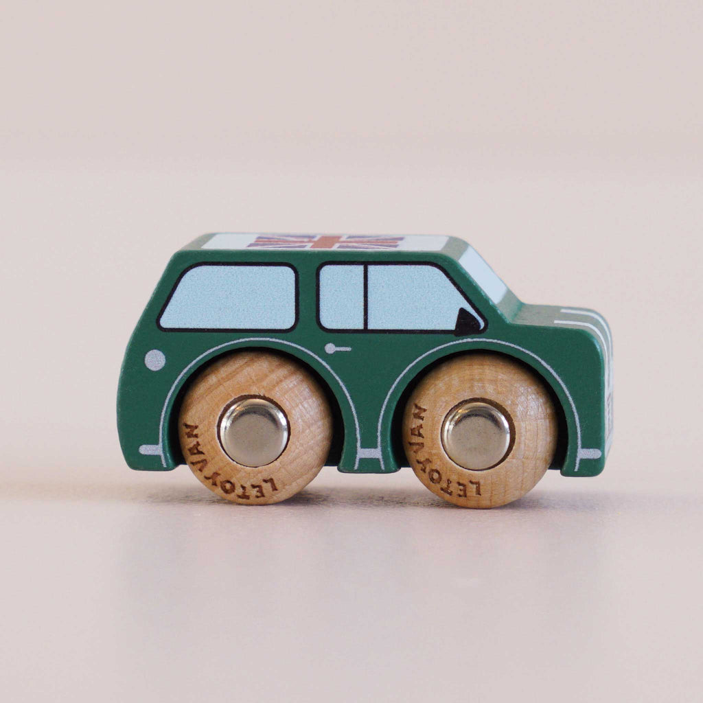 The No. 7 GT45 Molly, made in England, is a small green wooden car inspired by classic British toys, featuring black windows and wheels crafted from both wood and metal, presented against a light background.