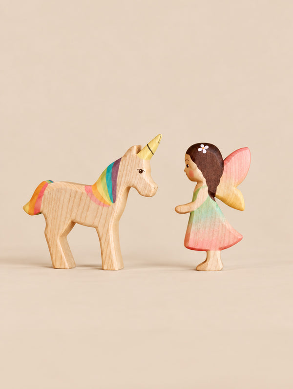 Handmade Holzwald Fairy Tale Set featuring a fairy with pink wings and a unicorn with a rainbow mane and tail facing each other.