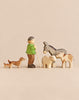 This Handmade Holzwald Shepherd & Farm Animals Set features a shepherd with a staff, two dachshunds, a donkey, a sheep, and a calf, all hand-carved from wood.