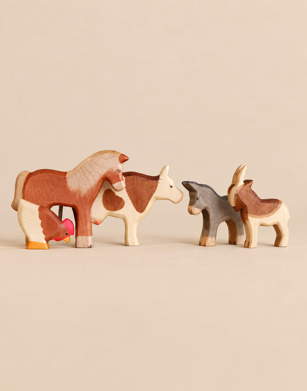 A set of Handmade Holzwald Farm Animals including a wooden horse, cow, donkey, goat, and chicken.