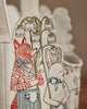 Close-up of embroidered fabric from the Coral & Tusk Easter Parade Basket, showing a red fox and white rabbit in clothes holding lily of the valley sprigs, set against a softly blurred background for added whimsy.