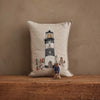 The Coral & Tusk Lighthouse Friends Pocket Pillow, featuring embroidered linen with a lighthouse and animals, stands against a brown textured wall with a decorative doll in front. Its cover meets Oeko-Tex Standard 100 safety standards.