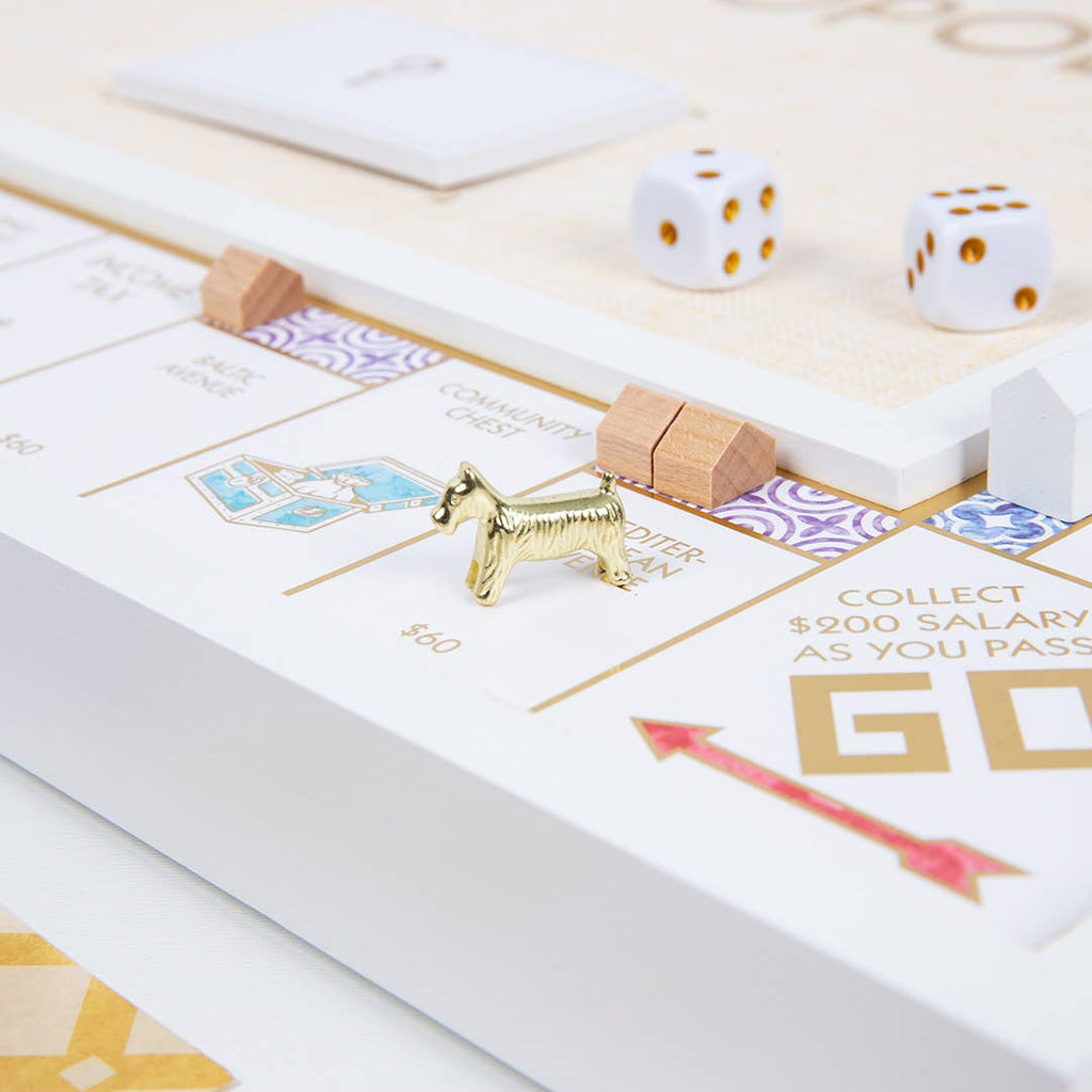 The Monopoly Bianco Edition board game featuring gold metal tokens, wooden houses, and white dice.
