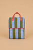 The Sticky Lemon Backpack Large | Stripes | Tickling Grass + Cloud Blue (ships in a week) is a rectangular backpack with vertical olive green and light blue stripes, red handles and trim, made from recycled PET bottles, and featuring adjustable shoulder straps. It is displayed against a plain beige background.