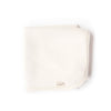The Organic Baby Blanket – Natural is a soft, folded, off-white, chemical-free blanket with rounded corners and a small "oolie" fabric tag on the edge, shown on a white background.