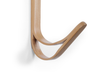 A close-up of the Coat Hanger - Tiger, a modern curved bamboo hook with a smooth light wood finish and sleek, minimalist design, mounted on a white wall.