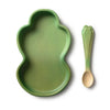 The Kendall the Kale Plate & Spoon Set is a green, frog-shaped baby dinnerware set featuring a non-toxic plate made from sustainable Hevea wood and a matching green spoon with a leaf-like handle—both elegantly displayed on a white background.