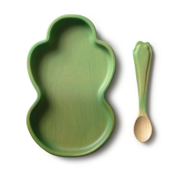 The Kendall the Kale Plate & Spoon Set is a green, frog-shaped baby dinnerware set featuring a non-toxic plate made from sustainable Hevea wood and a matching green spoon with a leaf-like handle—both elegantly displayed on a white background.