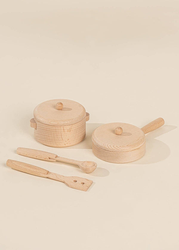 Two small wooden pots with lids and three wooden utensils—a spatula, spoon, and slotted spatula—are arranged on a light beige surface, showcasing the Wooden Pots and Pans Playset (6 Pcs), a delightful addition to any wooden play kitchen or kids cooking set.