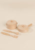 Two small wooden pots with lids and three wooden utensils—a spatula, spoon, and slotted spatula—are arranged on a light beige surface, showcasing the Wooden Pots and Pans Playset (6 Pcs), a delightful addition to any wooden play kitchen or kids cooking set.