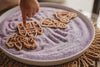 A child’s hand points at a wooden castle shape on purple sensory sand, with additional wooden shapes of a unicorn, crown, and dress also visible on the tray—all part of the Princess Cutter Set - Eco Playdough Tool. This enchanting and eco-friendly playdough cutter collection is designed to inspire imaginative princess-themed play while caring for the planet.