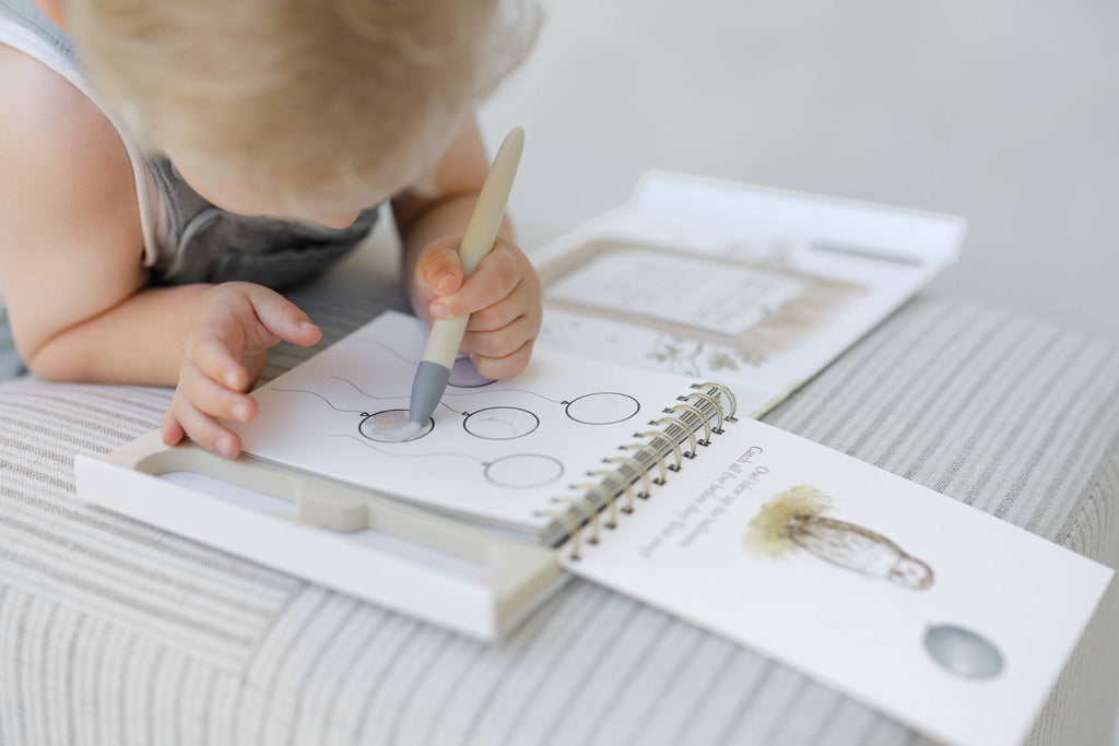 A child uses a water pen to color illustrations in a Winnie-the-Pooh: Pooh’s Birthday Surprise (Water Reveal) book.