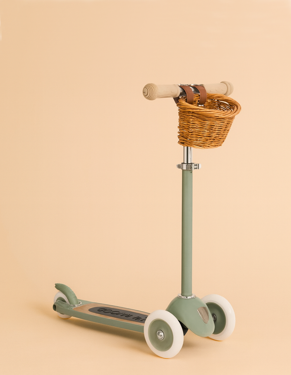The Banwood Scooter - Forest is a pastel green three-wheeled scooter featuring an adjustable handlebar and a wicker basket on the front, displayed against a light beige background.