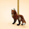 A handcrafted “Fox Cake Topper - Final Sale” collectible ceramic figurine featuring a candle holder with a beige candle on its back, displayed against a plain light beige background.
