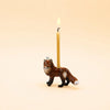 A handcrafted “Fox Cake Topper - Final Sale,” featuring a charming brown fox design with a lit candle on its back, is set against a plain beige background and makes for an adorable collectible.