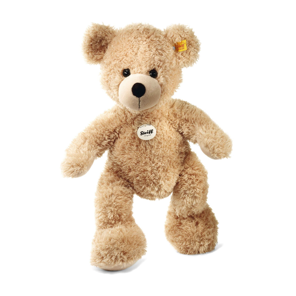 A handmade plush Steiff, Fynn Teddy Bear with light brown fur, featuring the brand's Button in Ear trademark, displayed against a white background.