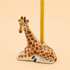 Introducing the Giraffe Cake Topper - Final Sale: a small, handcrafted ceramic giraffe figurine designed to lie down with a candle inserted into a holder on its back—making it the perfect porcelain cake topper or collectible. Photographed against a light beige background.