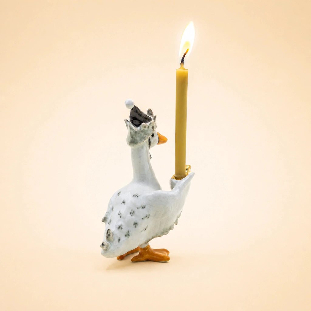 The Goodnight Goose Cake Topper—an adorable handcrafted ceramic figurine featuring a gray nightcap and a lit yellow candle—stands against a plain light beige background, making it a perfect keepsake birthday decoration and collectible.