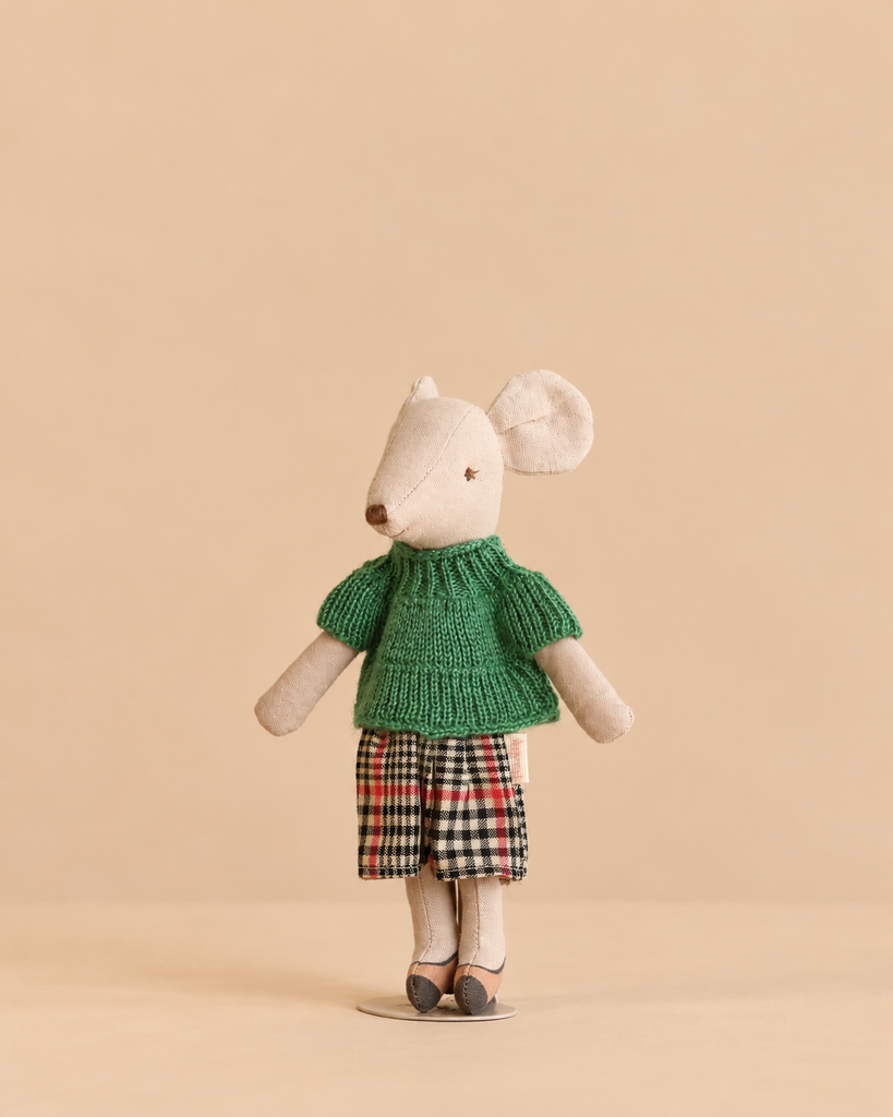 A Maileg Christmas Tea With Grandma Set featuring a mouse doll wearing a green sweater and a plaid skirt.